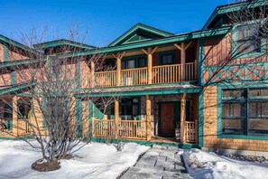A two-story building with a wooden facade, a balcony on the upper floor, and a snow-covered ground.