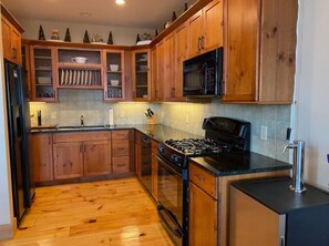 Kitchen features a gas stove, microwave, refrigerator, sink, and countertop with various kitchen items.