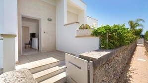A modern building with a stone wall, a door, and a small garden area. - 3046 Villetta Bianca by Barbarhouse (Otranto)