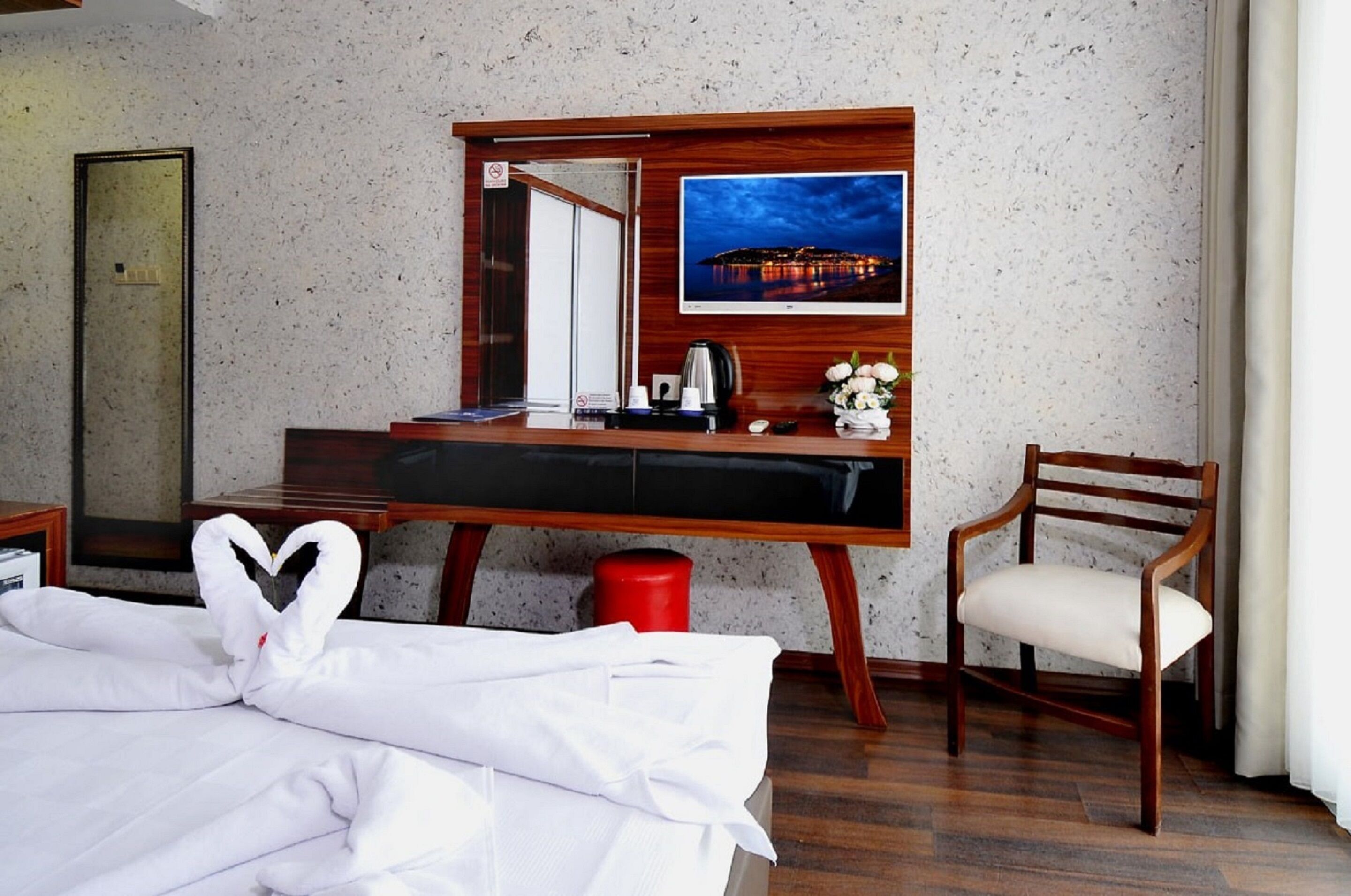 Una habitación de hotel con cama, escritorio, silla, televisión y espejo.