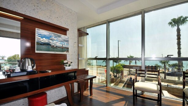 A modern kitchen with a wooden countertop, a painting, and a large window overlooking a beach. - UK Blue Coast Hotel  - Adults Only (Alanya)