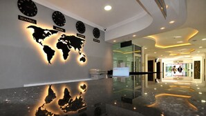 A modern lobby with a world map illuminated on the wall, clocks displaying different cities, and a glass partition. - UK Blue Coast Hotel  - Adults Only (Alanya)