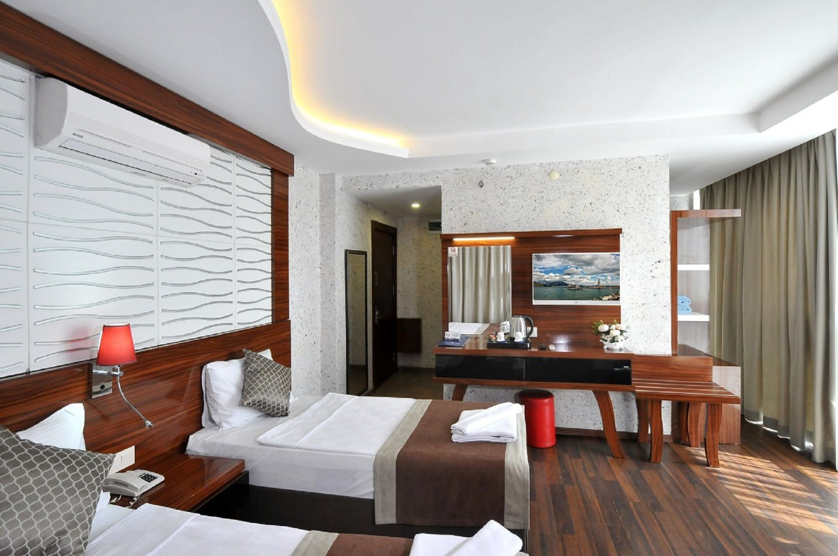 Una habitación de hotel con cama, mesita de noche, lámpara y un escritorio con silla.