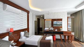 Una habitación de hotel con cama, mesita de noche, lámpara y un escritorio con silla.