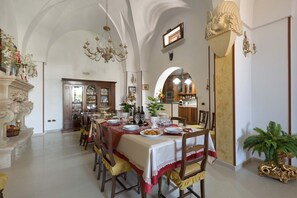A dining area with a table set for six, surrounded by wooden chairs. A chandelier hangs from the ceiling, and there is a large mirror above the table. - 2498 Villa Raffaella by Barbarhouse (Spongano)