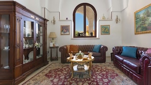 Un salon comprenant un grand meuble en bois, un canapé en cuir marron, une table basse ronde et un tapis à motifs.
