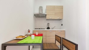 A compact kitchen with a dining area, featuring a table with a green placemat, a bench, and a small countertop. - 2214 Villetta Enea - Mono 1 by Barbarhouse (Castro)