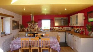 Una cocina compacta con isla central, sillas de madera, una mesa de comedor y una ventana que deja entrar luz natural.