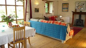 Una habitación acogedora con cama, una mesa de comedor con sillas, chimenea y ventana con cortinas.