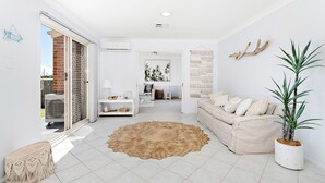 Un salon moderne avec un canapé beige, un tapis rond et une plante en pot.