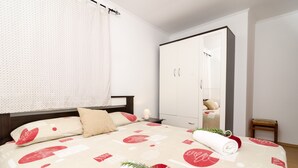 A bedroom with a bed, a wardrobe, a nightstand, and a small wooden chair.