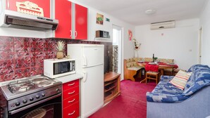 A compact kitchen with a stove, microwave, and refrigerator, adjacent to a dining area with a table set for two.