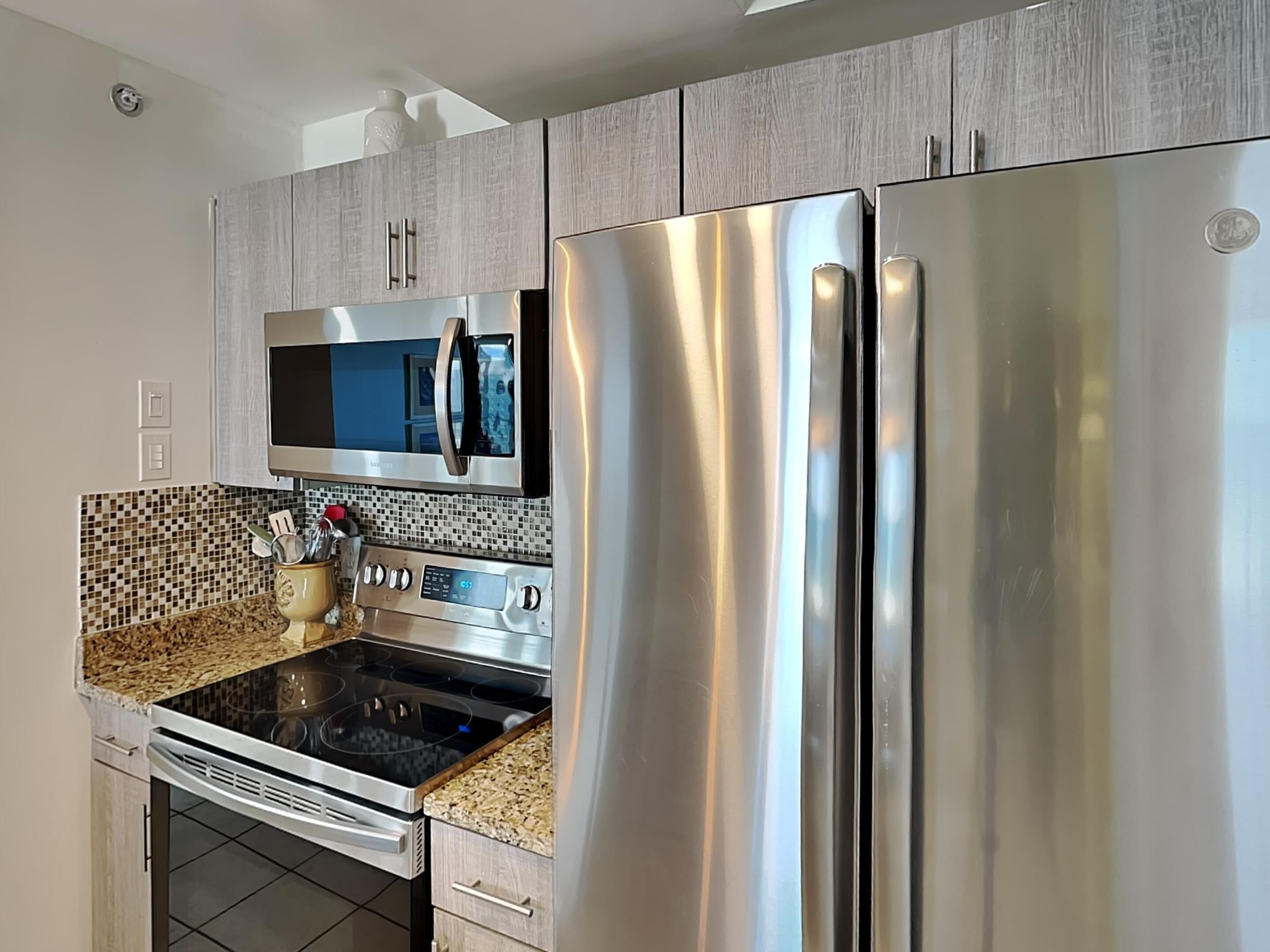 A modern kitchen with stainless steel appliances, a microwave, and a tiled backsplash.