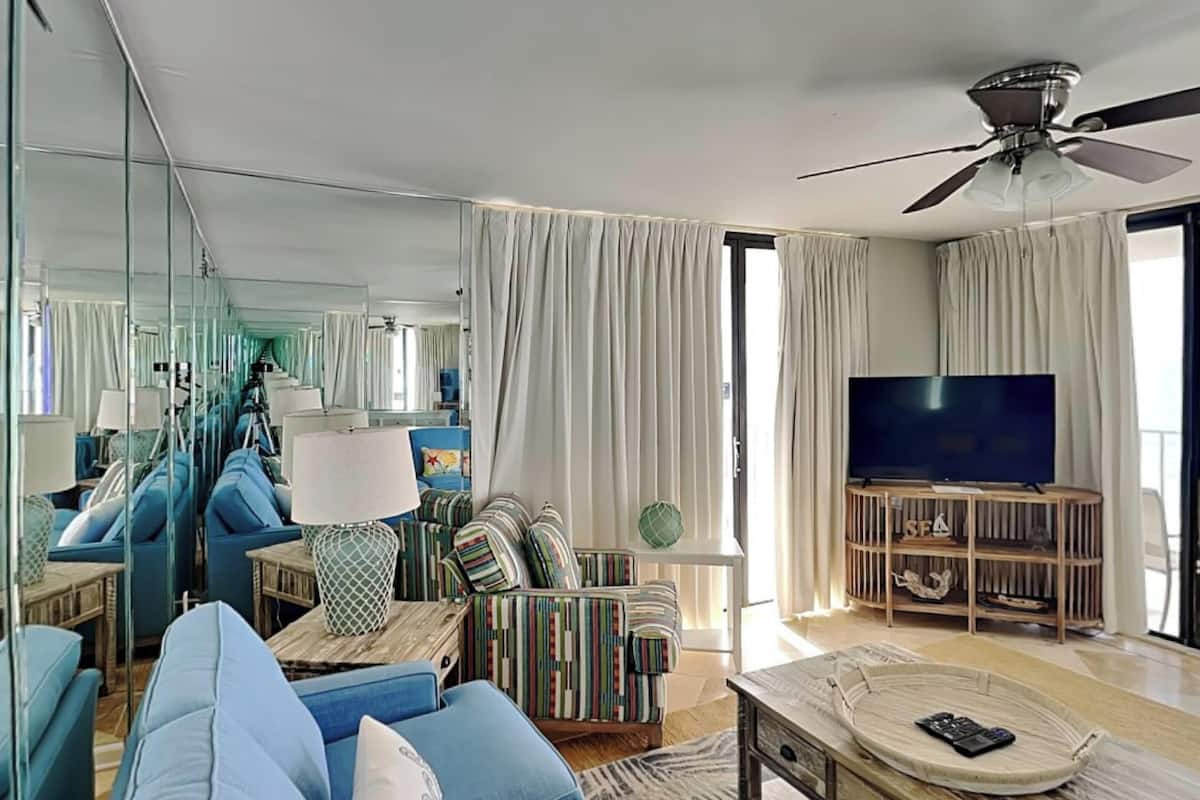 Ein modernes Wohnzimmer mit einer Couch, einem Fernseher und einem Deckenventilator.