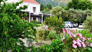 Una villa con techo de tejas rojas, rodeada de exuberante vegetación y montañas al fondo.