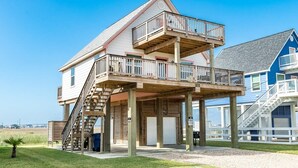 A two-story house with a balcony, a staircase, and a garage. - Seaside Sanctuary - Adorable Beach A-Frame, Decks! (Surfside Beach)
