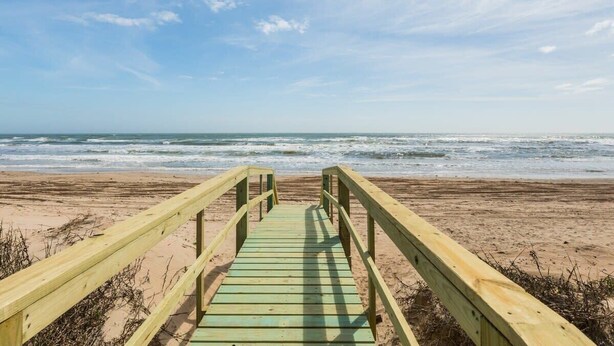A wooden boardwalk leading to a beach with the ocean in the background. - Seaside Sanctuary - Adorable Beach A-Frame, Decks! (Surfside Beach)
