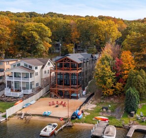 A waterfront property with a dock, boats, and a large house with multiple decks and a balcony.