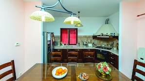 A modern kitchen with a dining table, chairs, and a bowl of fruit. - Villa Anka (Dubrovnik)