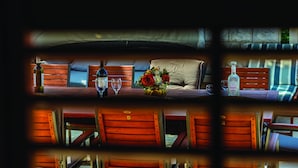 A cozy room with a wooden bench, a small table with a vase of flowers, and a bottle of liquor. - Villa Anka (Dubrovnik)