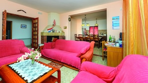 A living room with two pink sofas, a wooden coffee table, and a dining area with a table and chairs. - Villa Anka (Dubrovnik)