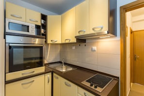 A compact kitchen with a microwave, oven, and stove.