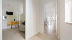 A spacious, well-lit hallway with a dining area featuring a table and chairs, and a kitchen area with a TV and tiled backsplash. - 3038 La Casa di Maristella- Bilo by Barbarhouse (Otranto)