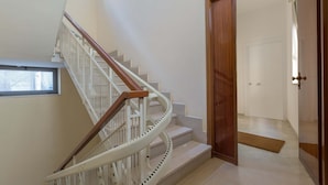 A spiral staircase with white railings and wooden handrails, leading to a room with a wooden door and a doormat on the floor. - 3038 La Casa di Maristella- Bilo by Barbarhouse (Otranto)