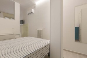 Un dormitorio con cama, radiador, equipo de aire acondicionado y espejo.