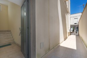 A narrow corridor with a set of stairs leading to a door, a tiled floor, and a clear blue sky visible through the window. - 3038 La Casa di Maristella- Bilo by Barbarhouse (Otranto)