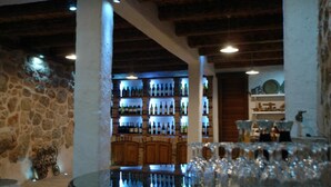 A bar area with shelves of bottles, a round table with glasses, and a stone wall. - Rilović House (Konavle)
