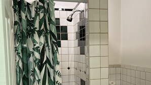 Une salle de bain avec douche, toilettes et murs carrelés.