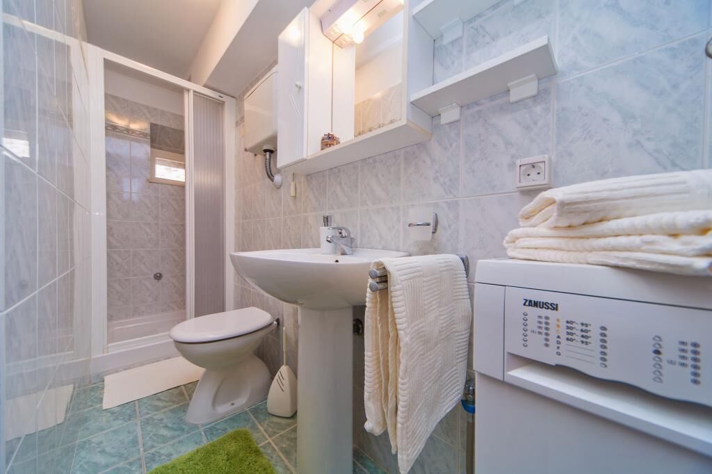 Un baño moderno con inodoro, lavamanos y zona de ducha.