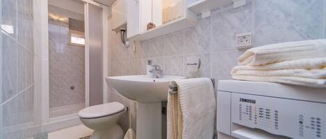 Un baño moderno con inodoro, lavamanos y zona de ducha.