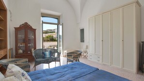 A bedroom with a large bed, two wicker chairs, a wooden cabinet, and a wardrobe. - 2999 La Casa in Piazzetta by Barbarhouse (Castro)