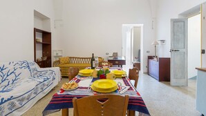 A dining area with a table set for four, a sofa, and a wooden cabinet. - 2999 La Casa in Piazzetta by Barbarhouse (Castro)