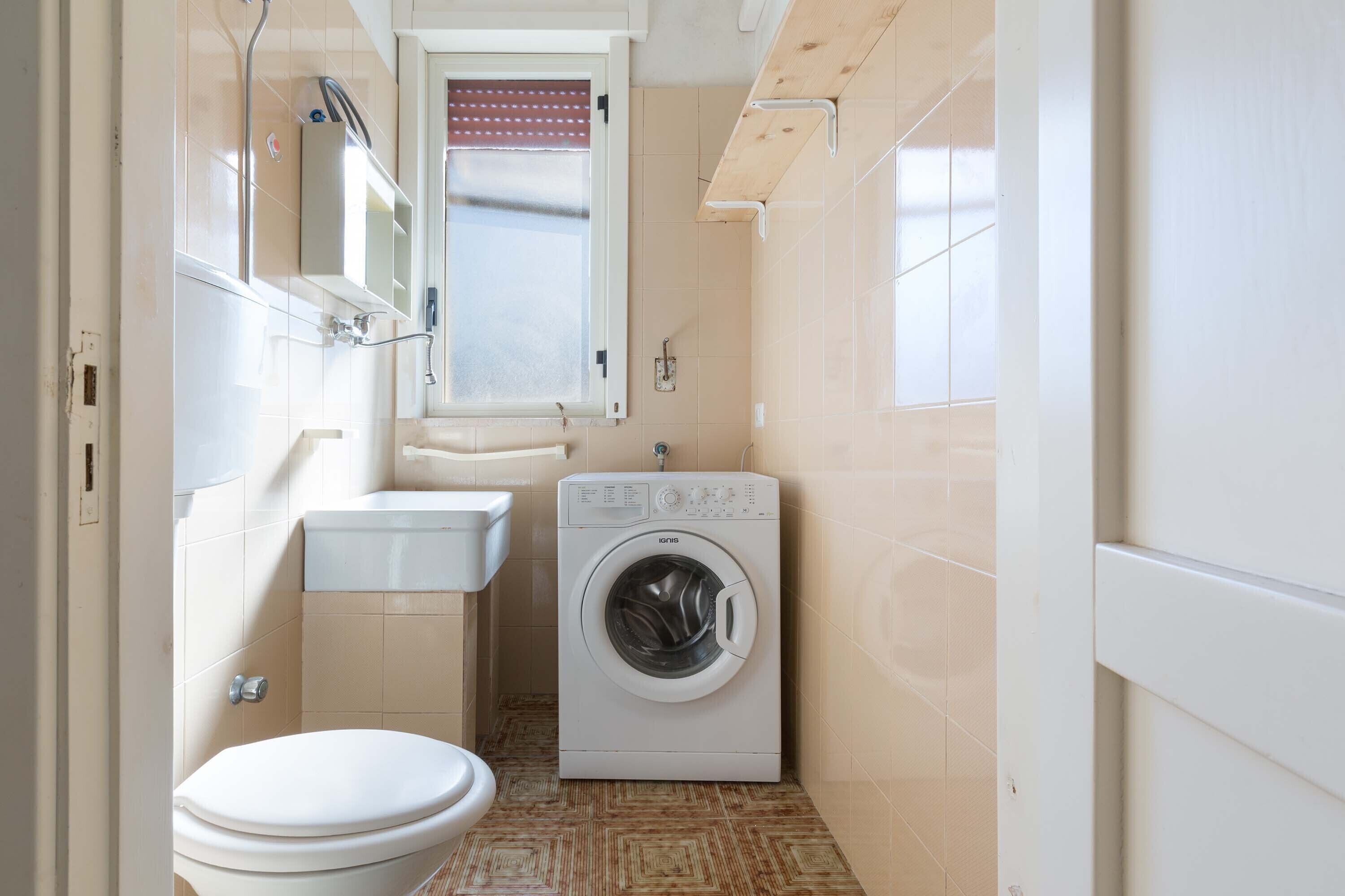 A compact bathroom with a toilet, sink, and washing machine.