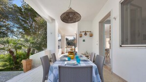 An outdoor dining area with a table set for four, surrounded by wicker chairs, under a woven ceiling light. - 2718 Villetta Soffio di Mare by Barbarhouse (Melendugno)
