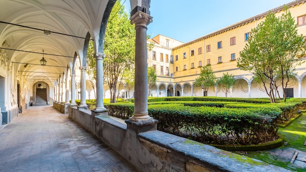 Une allée couverte, bordée de colonnes, et un espace aménagé en jardin.