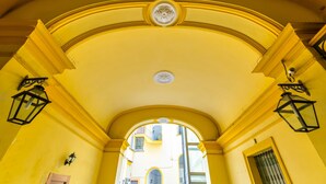 Un couloir en arc de cercle aux murs jaunes et orné de moulures décoratives.