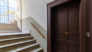 Un escalier aux marches de marbre menant à une porte en bois sombre.