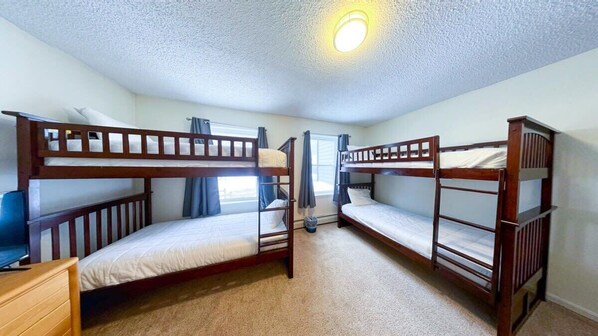A room with three bunk beds, a desk, and a chair.