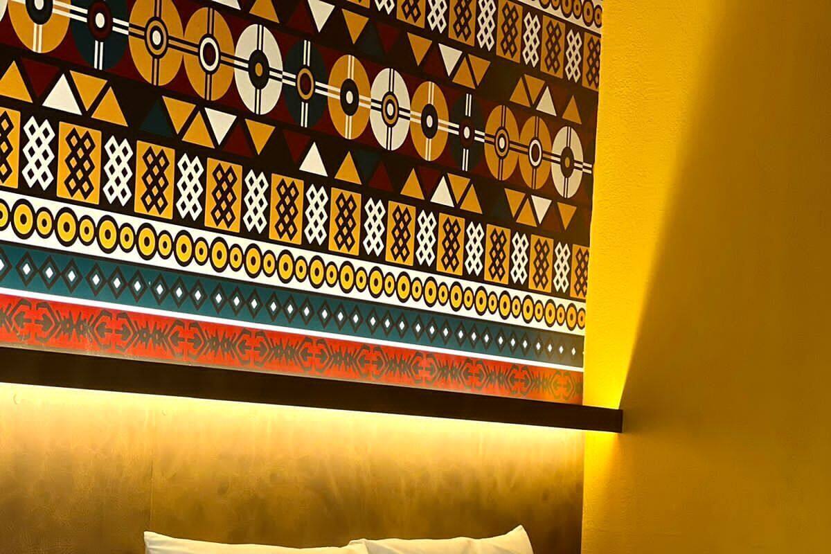 Habitación de hotel con cama, almohadas, control remoto, teléfono y un adorno en la pared.