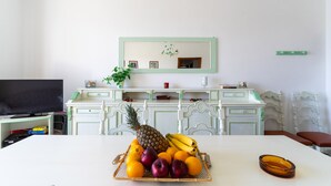 A dining area with a table set for two, a television on a stand, and a fruit basket on the table. - 2993 La Casa di Tiziana by Barbarhouse (Melendugno)