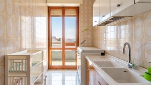 A kitchen with a sink, stove, and cabinets. There is a door leading to a balcony. - 2993 La Casa di Tiziana by Barbarhouse (Melendugno)