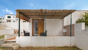 Eine moderne Außenpatio mit einer Holz-Pergola, einer Sitzgelegenheit mit Tisch und Stühlen und Blick auf ein Wohngebäude im Hintergrund.