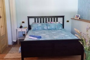 A bedroom with a bed, a nightstand, a lamp, and a small shelf with a picture. - Summer Sale! Lovely 3-bed Apartment in Spoleto (Spoleto)