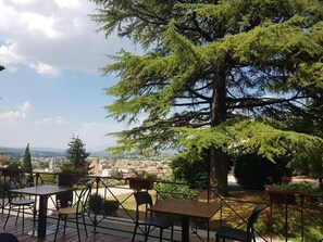 An outdoor seating area with tables and chairs, overlooking a cityscape and mountains. - Summer Sale! Lovely 3-bed Apartment in Spoleto (Spoleto)