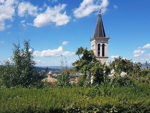 A tower with a pointed roof, surrounded by greenery and a clear sky. - Summer Sale! Lovely 3-bed Apartment in Spoleto (Spoleto)