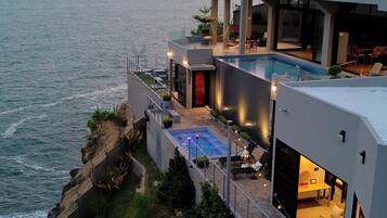 Uma propriedade costeira moderna com piscina, área de estar externa e vista para o oceano.